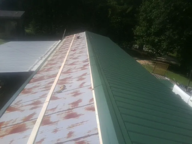 Old rusted panels beside newly installed green metal roofing — Wind Damage Roof Repair by Roofing Brothers in Richland